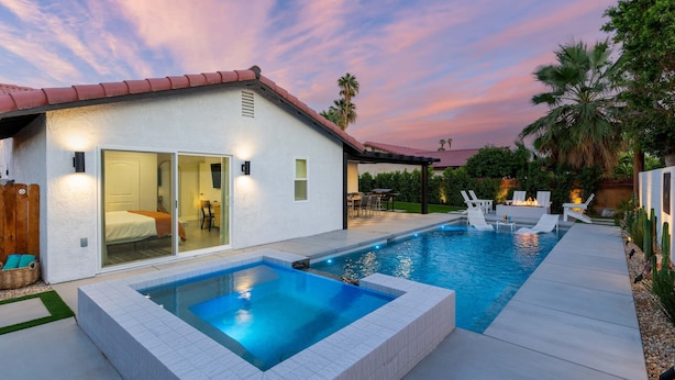 A modern house with a swimming pool, a patio with outdoor furniture, and a view of the sunset. - 3-bedroom Fireplace Stunning Spanish Home (Indio)