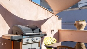 A barbecue grill, outdoor chairs, and a potted plant on a balcony. - Nicu Amuri con Terrazza a Noto by Wonderful Italy (Noto)