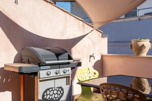 A barbecue grill, outdoor chairs, and a potted plant on a balcony. - Nicu Amuri con Terrazza a Noto by Wonderful Italy (Noto)