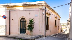 A building with a closed door, a no parking sign, and a potted plant on the sidewalk. - Nicu Amuri con Terrazza a Noto by Wonderful Italy (Noto)