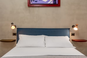 A neatly made bed with white linens, a blue headboard, and two bedside tables with wall-mounted lamps. - Nicu Amuri con Terrazza a Noto by Wonderful Italy (Noto)