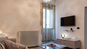 A modern living room with a glass coffee table, a sofa, a TV mounted on the wall, and a radiator. - Nicu Amuri con Terrazza a Noto by Wonderful Italy (Noto)