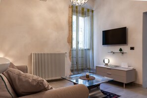 A modern living room with a glass coffee table, a sofa, a TV mounted on the wall, and a radiator. - Nicu Amuri con Terrazza a Noto by Wonderful Italy (Noto)