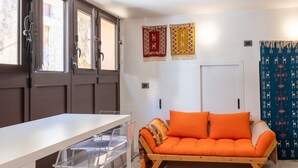 A room with a wooden sofa, a white table, and a window with curtains. - Nicu Amuri con Terrazza a Noto by Wonderful Italy (Noto)