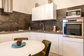 Una cucina moderna con mobili bianchi, un forno a microonde, un forno e un piano cottura a gas.