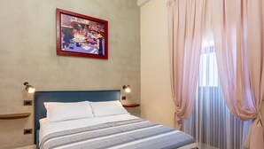 A neatly made bed with a striped blanket, a blue headboard, and a framed picture on the wall. - Nicu Amuri con Terrazza a Noto by Wonderful Italy (Noto)