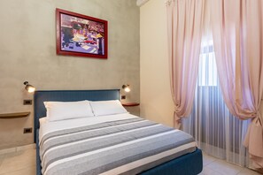 A neatly made bed with a striped blanket, a blue headboard, and a framed picture on the wall. - Nicu Amuri con Terrazza a Noto by Wonderful Italy (Noto)
