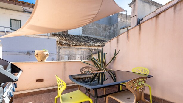 A patio with a table and chairs, a grill, and a potted plant. - Nicu Amuri con Terrazza a Noto by Wonderful Italy (Noto)