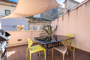 A patio with a table and chairs, a grill, and a potted plant. - Nicu Amuri con Terrazza a Noto by Wonderful Italy (Noto)