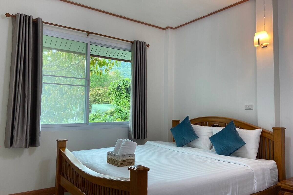 Un dormitorio con cama de madera, ropa de cama blanca y una ventana con cortinas.