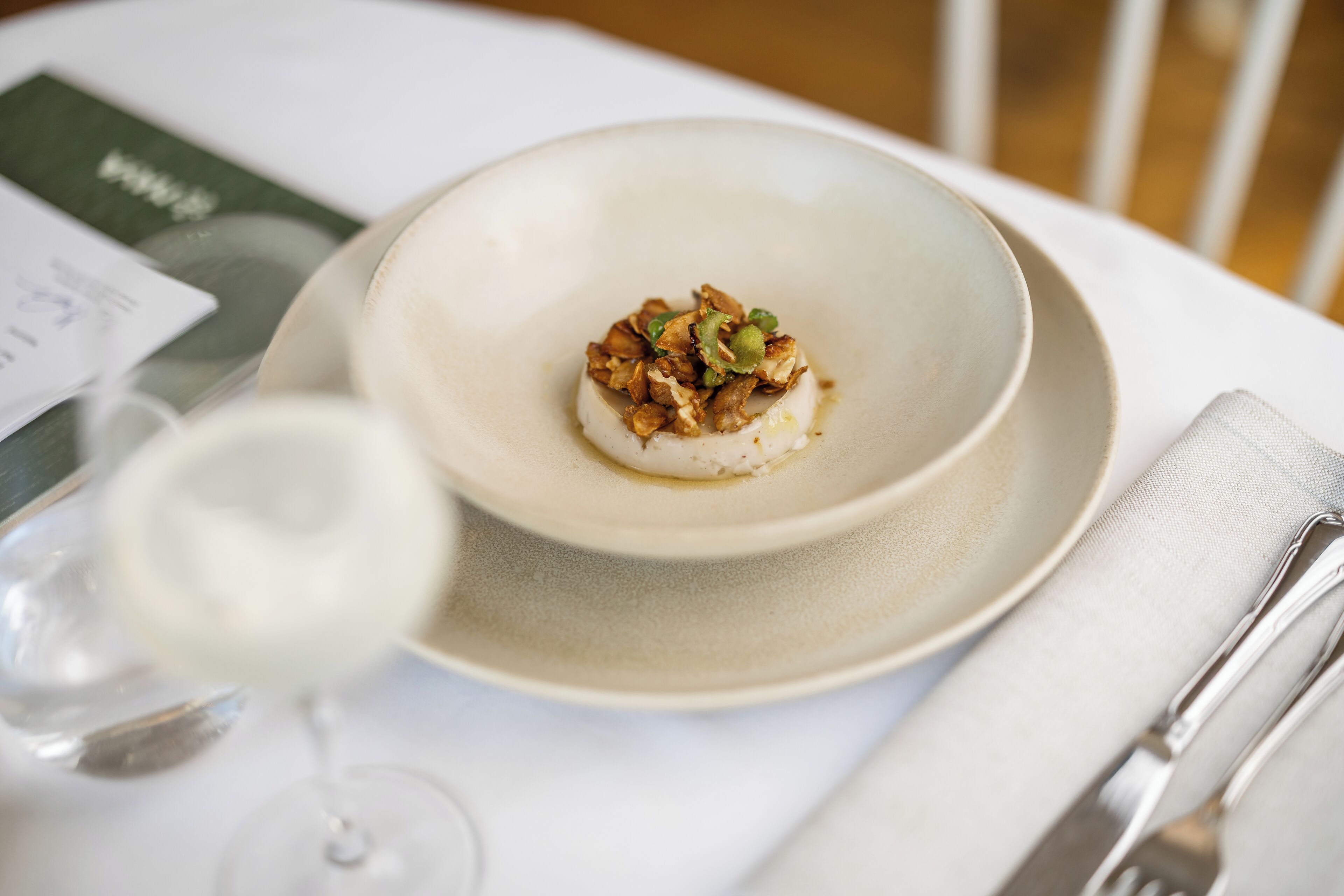 A dining table with a plate of food, a wine glass, and a menu.