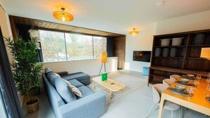 Un salon moderne avec un canapé, une table basse et un coin repas comprenant des chaises et une table mise pour le repas.