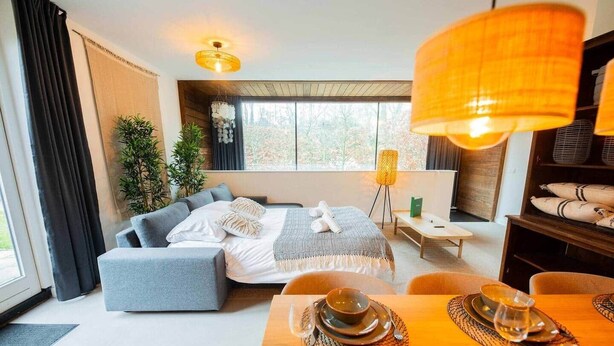 Une chambre d’hôtel moderne équipée d’un lit, d’un coin salon, d’une table à manger et de grandes fenêtres.
