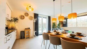 Une cuisine moderne avec un coin repas, de grandes fenêtres et une vue sur l’extérieur.