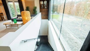 Un intérieur moderne avec un escalier, un canapé, une table basse et une vue sur l’extérieur.