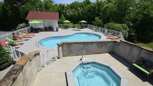 Piscina con un pequeño jacuzzi, rodeada por una valla y sillas de descanso.