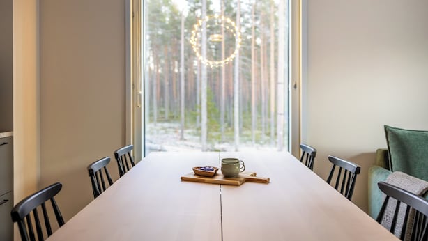 Une table à manger avec des chaises, un bol et une tasse posés sur une planche en bois.