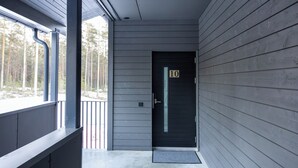 Un bâtiment moderne à l’extérieur gris, avec une porte noire portant le numéro 10 et un porche abrité.