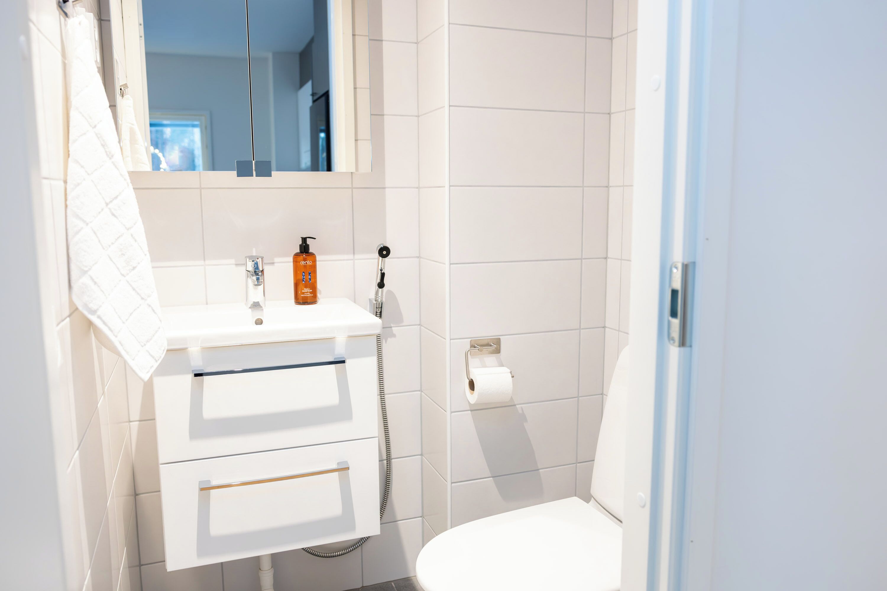 A bathroom with a white sink, a mirror, a towel, and a toilet.