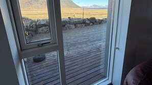 Una stanza con un'ampia finestra che si affaccia su un paesaggio roccioso e montagne lontane.