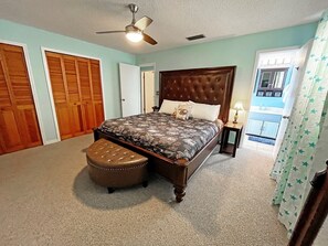 Relax in this serene bedroom with a large bed, tufted headboard, and patterned bedspread. A comfortable bench invites you to sit and unwind.