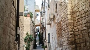 A narrow alleyway with stone buildings, potted plants, and a visible door on the left. - Dimora D'Archi in the beating heart of Bari's Borgo Antico  (Bari)
