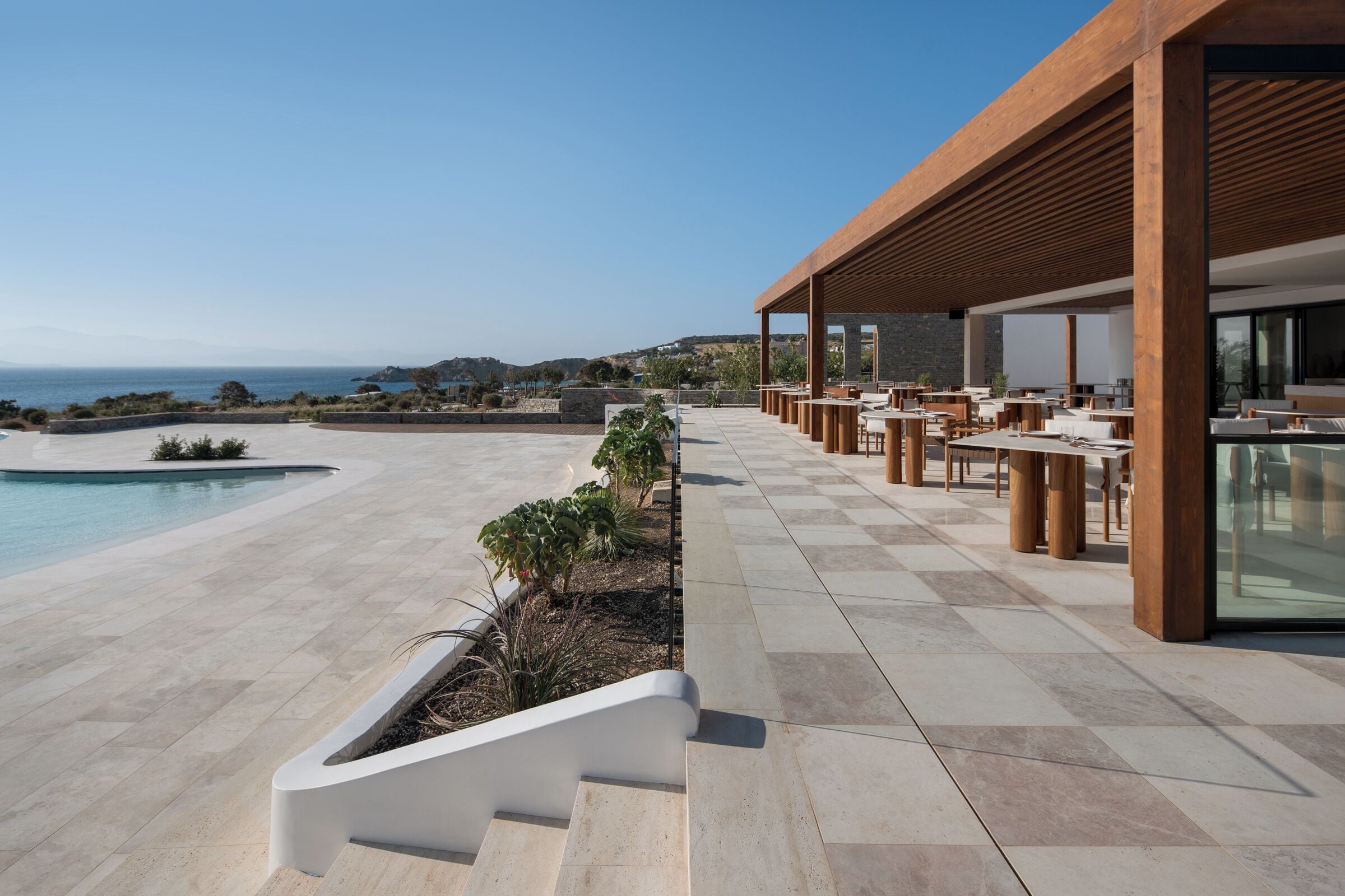 A modern outdoor seating area with a pool and a view of the sea.
