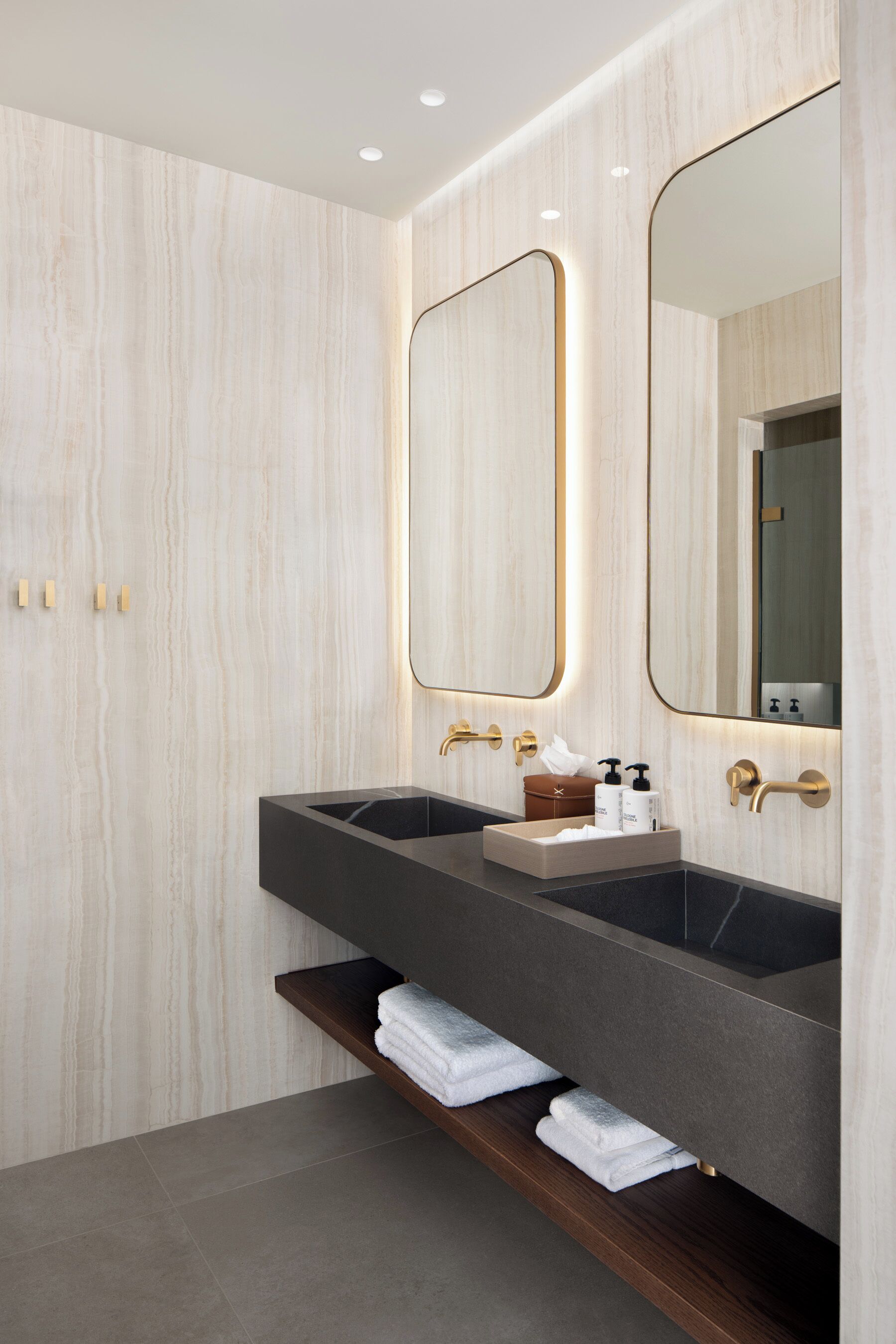 A modern bathroom with two sinks, a mirror, and a shelf with towels.