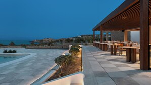 Una terraza exterior con piscina, zona de estar y vista al mar.