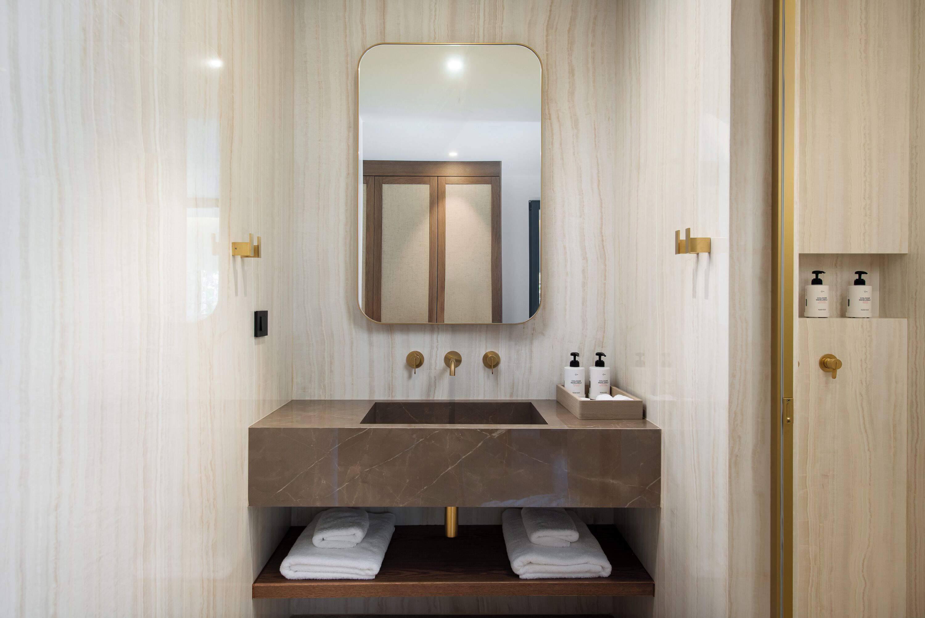 A bathroom with a marble sink, a mirror, and a wooden vanity.