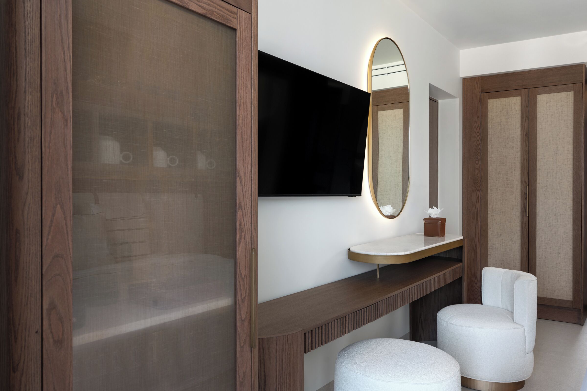Un bagno moderno con un mobile bagno in legno, uno specchio grande e due sedie bianche.
