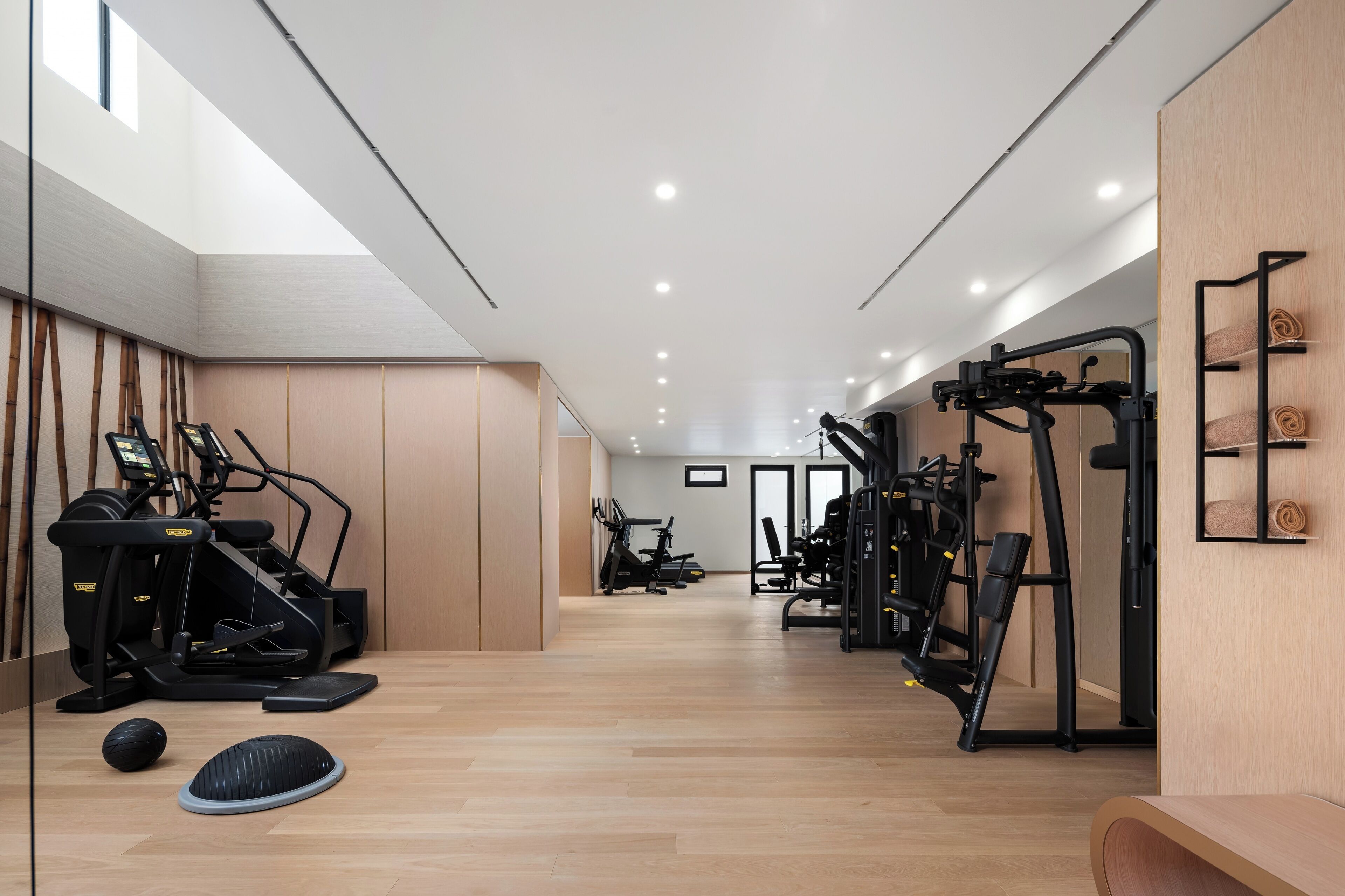 Uma academia moderna com equipamentos de cardio, estações de musculação e piso de madeira.