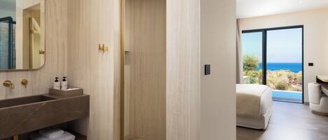 A modern bathroom with a large mirror, a vanity with a sink, and a shower area.