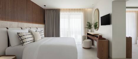 A modern hotel room with a large bed, a wooden headboard, a flat-screen TV, a bedside table, and a large window with curtains.