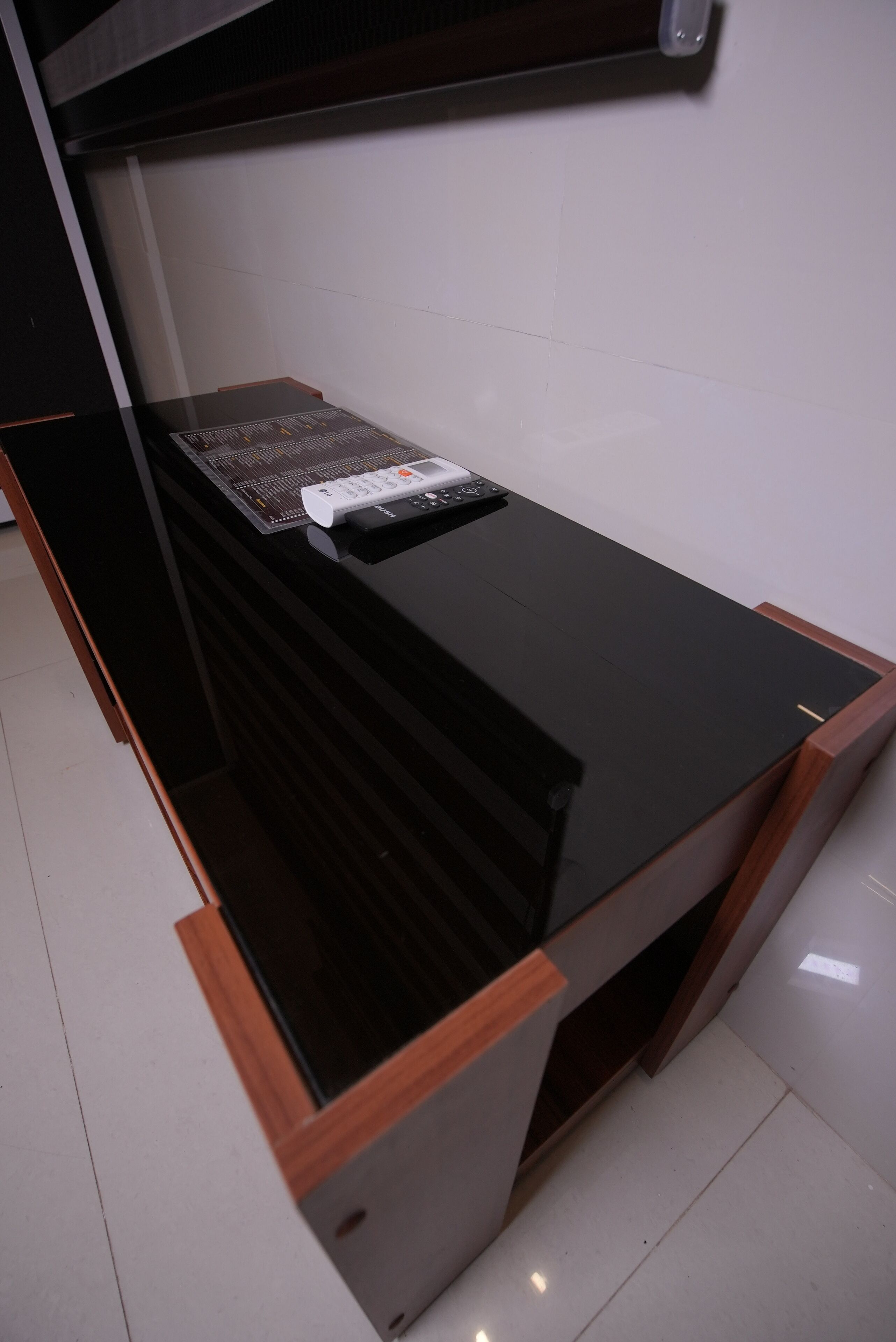Un bureau noir, à la surface brillante, doté d’un panneau de commande et sur lequel est posé un appareil blanc.
