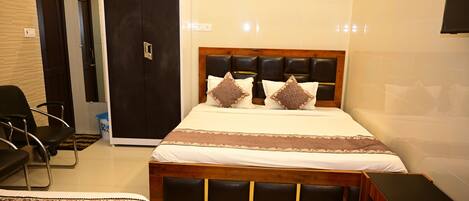 A bedroom with a bed, a wardrobe, a desk, and a chair.
