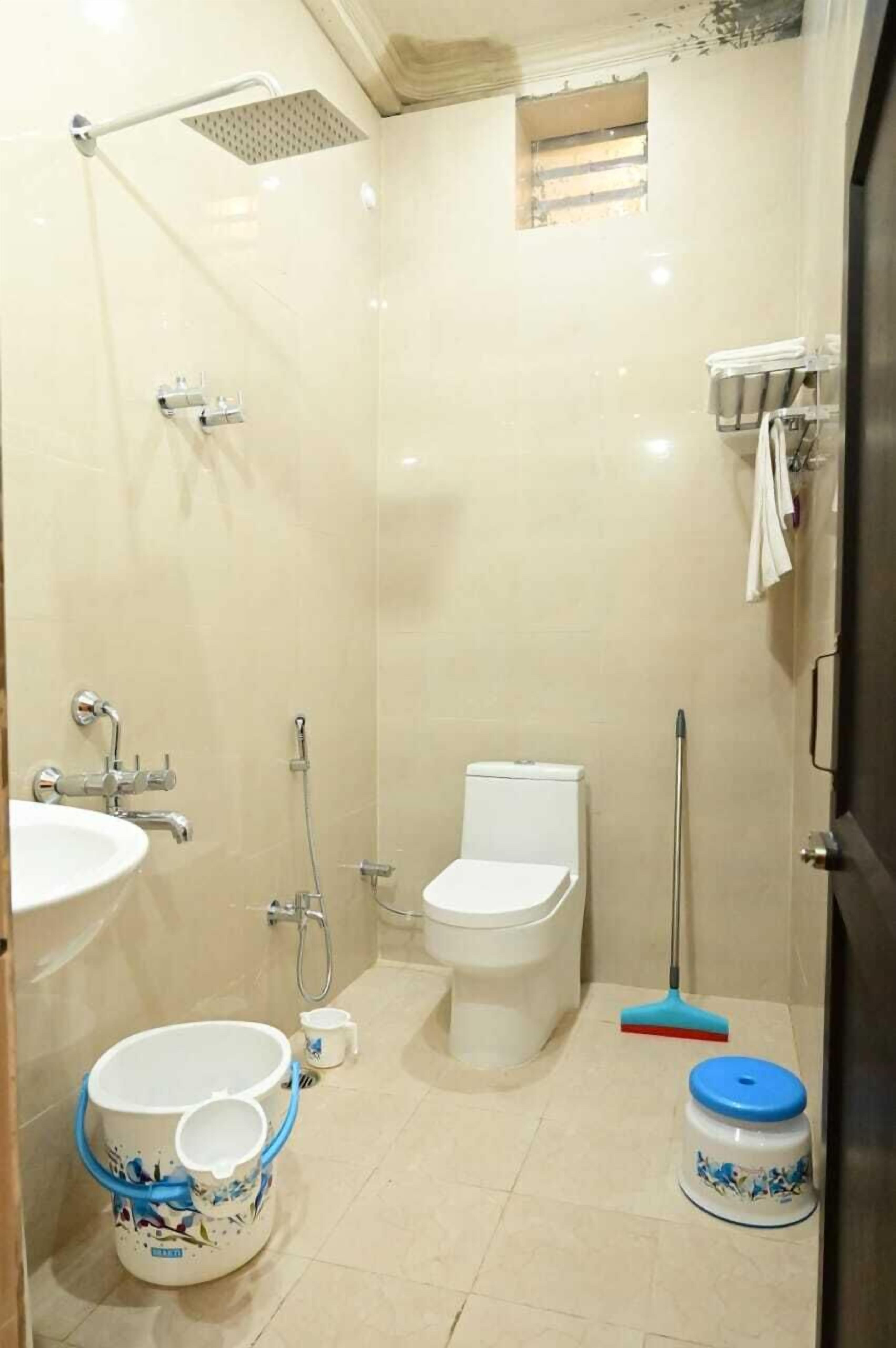 Ein kleines Badezimmer mit Fliesen, Toilette, Waschbecken, Dusche und einem Mopp.