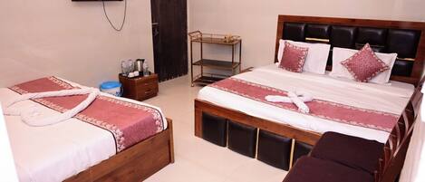A hotel room with two single beds, a wooden headboard, a TV mounted on the wall, a small table with a tray, and a bench.