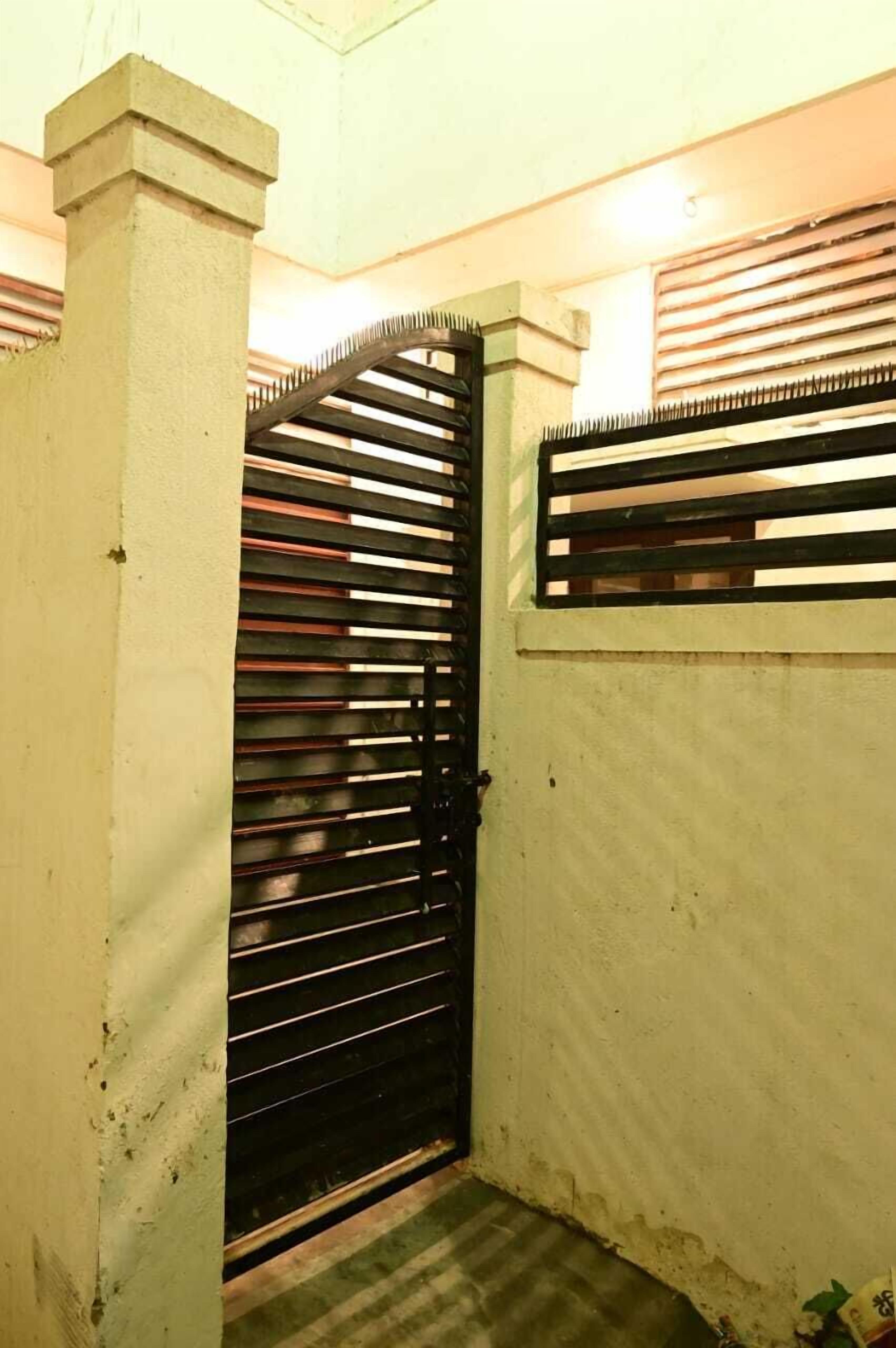 Egy szűk, zárt tér, fekete fém kapuval és fehér fallal.