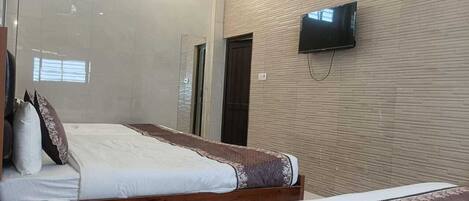 Una habitación de hotel con una cama, un televisor montado en la pared y una puerta.