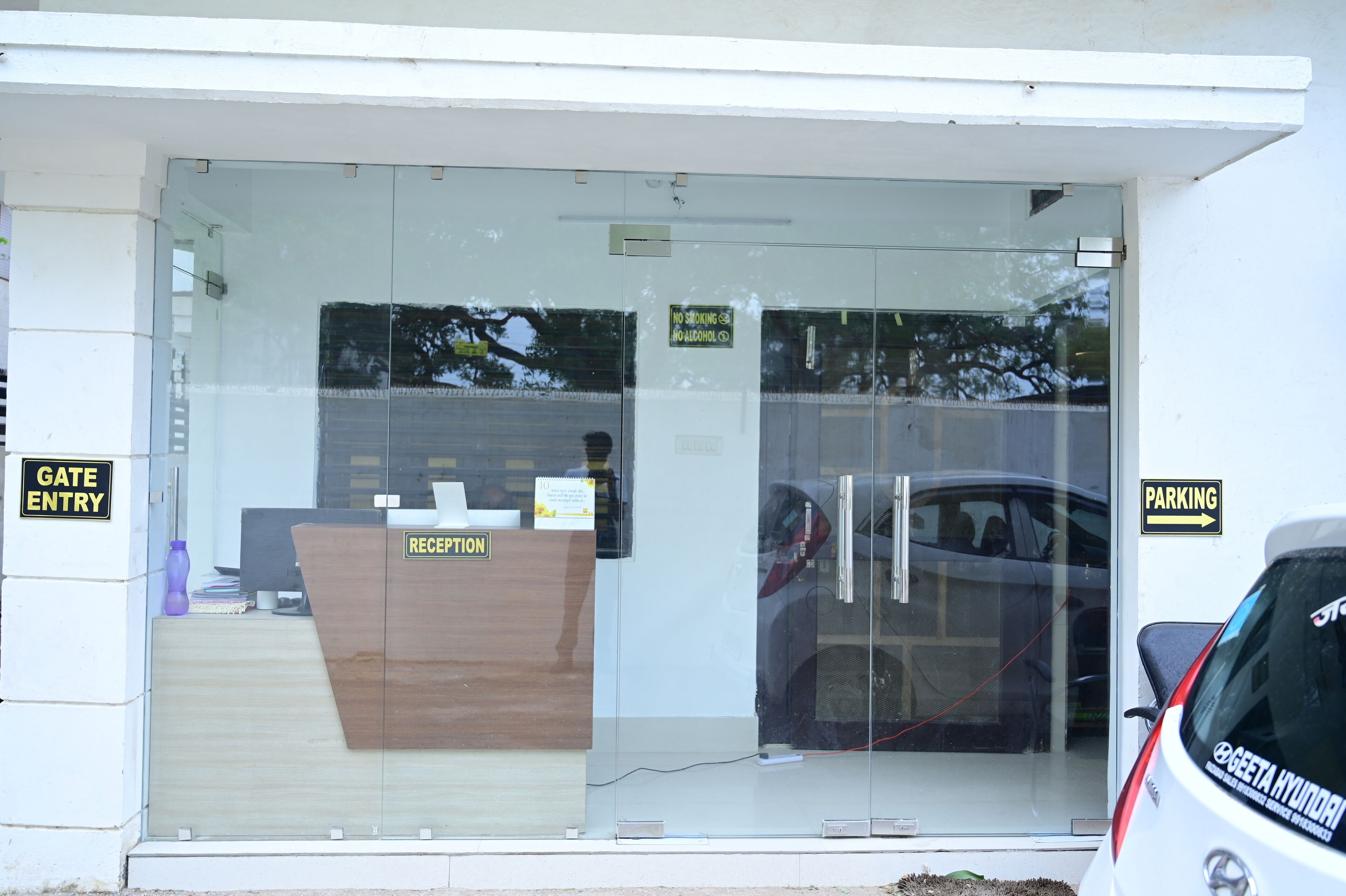 A reception desk with a glass door, a parking sign, and a gate entry sign.