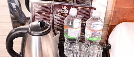A wooden chest with a kettle, two cups, and water bottles on a tray.