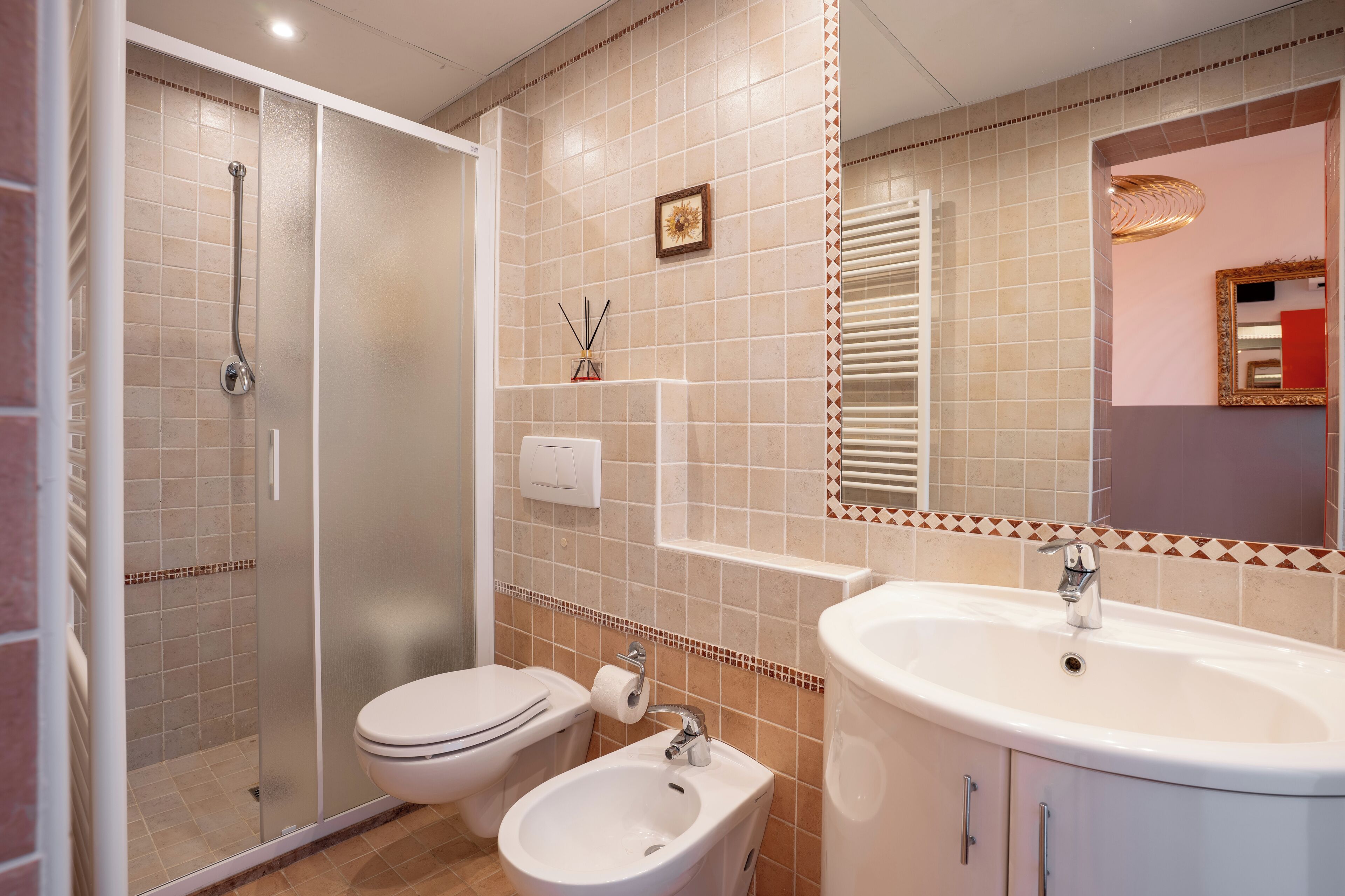 A bathroom with a glass-enclosed shower, a toilet, a sink, and a mirror.