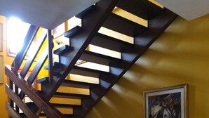 A wooden staircase with a yellow wall and a framed painting. - Villa Anna (Santarcangelo di Romagna)