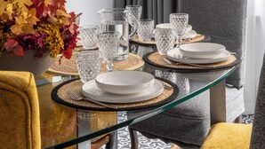 A dining area with a glass table, grey upholstered chairs, and a vase with autumn leaves. - "LE DUE CUPOLE" LUXURY APARTMENT "A" IN THE CENTER OF ROME (Roma)