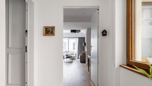 A hallway with a wooden floor, white walls, and a door leading to a living area with a sofa and a coffee table. - "LE DUE CUPOLE" LUXURY APARTMENT "A" IN THE CENTER OF ROME (Roma)