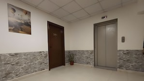 A hallway with a marble wall, a door labeled "301", and an elevator. - El RAYYAN HOTEL (Amman)