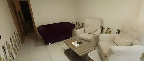Ein Wohnzimmer mit einem dunkelgrauen Sofa, einem hellen Sessel und einem Holztisch.