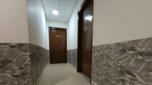 A hallway with a marble wall, a tiled floor, and a door with the number 307. - El RAYYAN HOTEL (Amman)