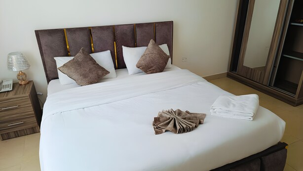 A neatly made bed with a headboard, pillows, and a folded towel. - El RAYYAN HOTEL (Amman)